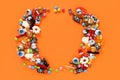 Halloween round wreath made of assorted candies. Orange background with copy space in middle.