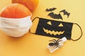 Halloween 2020 safe creative celebration. Evil face mask, pumpkin in mask, disinfection gel bottle Royalty Free Stock Photo