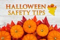 Halloween Safety Tips message with red and orange fall leaves and a pumpkins on weathered wood