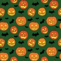 Halloween seamless pattern with orange pumpkins carved faces and black bats on green background Royalty Free Stock Photo