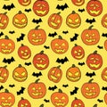 Halloween seamless pattern with orange pumpkins carved faces and black bats on light yellow background Royalty Free Stock Photo