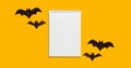 Halloween set decorations with bat and mock up empty notebook list on yellow background. Holiday party composition