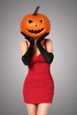 Halloween. lady in red with big pumpkin on head.