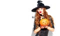 Halloween. witch with bright holiday makeup. Beautiful young woman posing in witches costume with pumpkin lantern