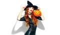 Halloween. witch with bright holiday makeup. Beautiful young woman posing in witches costume with pumpkin lantern Royalty Free Stock Photo