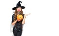 Halloween. witch with bright holiday makeup. Beautiful young woman in witches costume with pumpkin lantern pointing hand Royalty Free Stock Photo