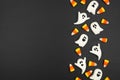 Halloween side border of candy corn and spooky chocolate ghosts on a black background