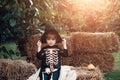 Halloween skeleton kid. Boy sitting on the haystack. Happy day. Little child enjoy walk. Happy laughing child in costume