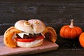 Halloween spider hamburger with onion ring legs against dark wood