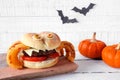 Halloween spider hamburger with onion ring legs against white wood