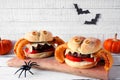 Halloween spider hamburgers with onion ring legs, table scene against white wood