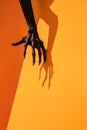 Halloween spooky background. Monster hand bursting through orange paper wall.