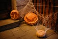 Halloween street decor. Carved pumpkins with scary faces and cobweb in dark. Modern festive decoration of european city street.