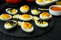 Halloween stuffed eggs with cheese and mustard on a black stone. Royalty Free Stock Photo