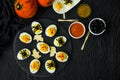 Halloween stuffed eggs with cheese and mustard on a black stone. Royalty Free Stock Photo