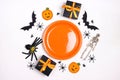 Halloween table setting with orange plate, spooky decorations and gifts on white table Royalty Free Stock Photo