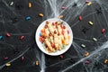 Halloween tasty cookies in form of witches fingers and colorful candies on black background with spider web. Halloween food