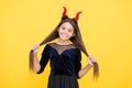 Halloween teen girl in red imp horns hold hair and playing trick o treat, happy halloween fun