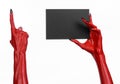 Halloween theme: Red devil hand with black nails holding a blank black card on a white background Royalty Free Stock Photo