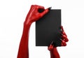 Halloween theme: Red devil hand with black nails holding a blank black card on a white background Royalty Free Stock Photo