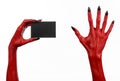 Halloween theme: Red devil hand with black nails holding a blank black card on a white background Royalty Free Stock Photo