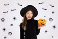 Halloween theme, young asian pretty woman in black halloween costume wearing witch hat holding orange pumpkin posing smiling on Royalty Free Stock Photo