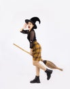 Halloween theme, young pretty asian girl in black dress wearing witch hat and holding broom posing on white background Royalty Free Stock Photo