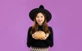 Halloween theme, young pretty asian woman in black long sleeve t-shirt black lip wearing witch hat holding pumpkin posing smiling Royalty Free Stock Photo