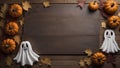 A Halloween themed background of a wood table with pumpkins, leaves and ghosts surrounding copy space