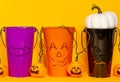 Three Halloween themed buckets with jack o lantern lights and white pumpkin against an orange background Royalty Free Stock Photo