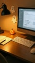 Halloween themed home office desk featuring a glowing jack-o'-lantern, ghost decorations, a computer, keyboard, notebook, and Royalty Free Stock Photo