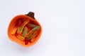 Halloween treats gummy worms in pumpkin bowl. Colorful jelly candies on white background. Top view Royalty Free Stock Photo