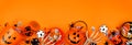 Halloween trick or treat bottom border with jack o lantern pails and candy over an orange banner background Royalty Free Stock Photo