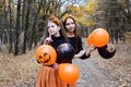Halloween. Two young girls in orange skirts with black and orange balloons with drawings on the background of the autumn forest