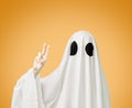 Halloween ghost showing peace gesture on yellow background.