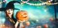 Halloween witch with a carved pumpkin and magic lights in a forest Royalty Free Stock Photo
