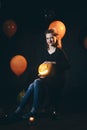 Halloween Witch with a carved Pumpkin and magic lights in a dark forest. Beautiful young surprised woman in witches hat Royalty Free Stock Photo