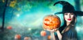 Halloween witch with a carved pumpkin and magic lights in a forest Royalty Free Stock Photo