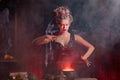 Halloween Witch with cauldron. Beautiful young woman conjuring, making witchcraft