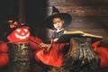 Halloween. witch child conjures with book of spells, magic wand and pumpkins