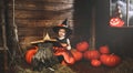 Halloween. witch child conjures with book of spells, magic wand and pumpkins Royalty Free Stock Photo