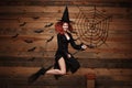 Halloween witch concept - Happy Halloween red hair Witch holding magic broomstick flying gesture over old wooden studio background