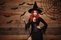 Halloween witch concept - Happy Halloween red hair Witch holding posing with magic broomstick over old wooden studio background.