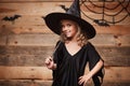 Halloween Witch concept - little witch child enjoy playing with magic wand. over bat and spider web background. Royalty Free Stock Photo