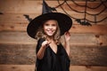 Halloween Witch concept - little witch child enjoy playing with magic wand. over bat and spider web background. Royalty Free Stock Photo