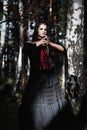 Halloween Witch in a dark forest. Beautiful young woman in witches costume . Halloween art design. Horror Background For Halloween