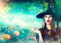 Halloween witch pointing hand over dark magic field with pumpkins