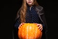 Halloween Witch with Pumpkin on black background. Beautiful young surprised woman in witches hat and costume holding Royalty Free Stock Photo