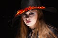 Halloween. Witch with a spider on his hat on black background. Beautiful young surprised woman in witches hat and Royalty Free Stock Photo