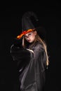 Halloween. Witch with a spider on his hat on black background. Beautiful young surprised woman in witches hat and Royalty Free Stock Photo